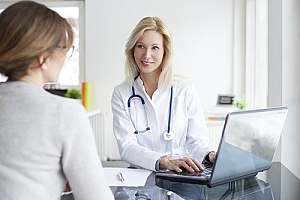 Doctor at computer talking to young woman