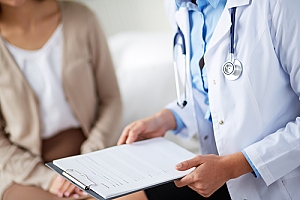 Doctor holding clipboard with form or results while talking to patient