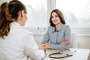 Woman sitting at desk consulting medical professional about endometrial biopsy