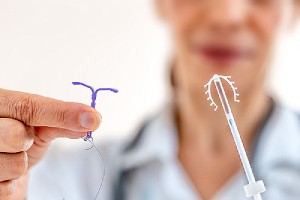 A female doctor is holding two types of IUD. IUDs can prevent pregnancy for up to ten years.