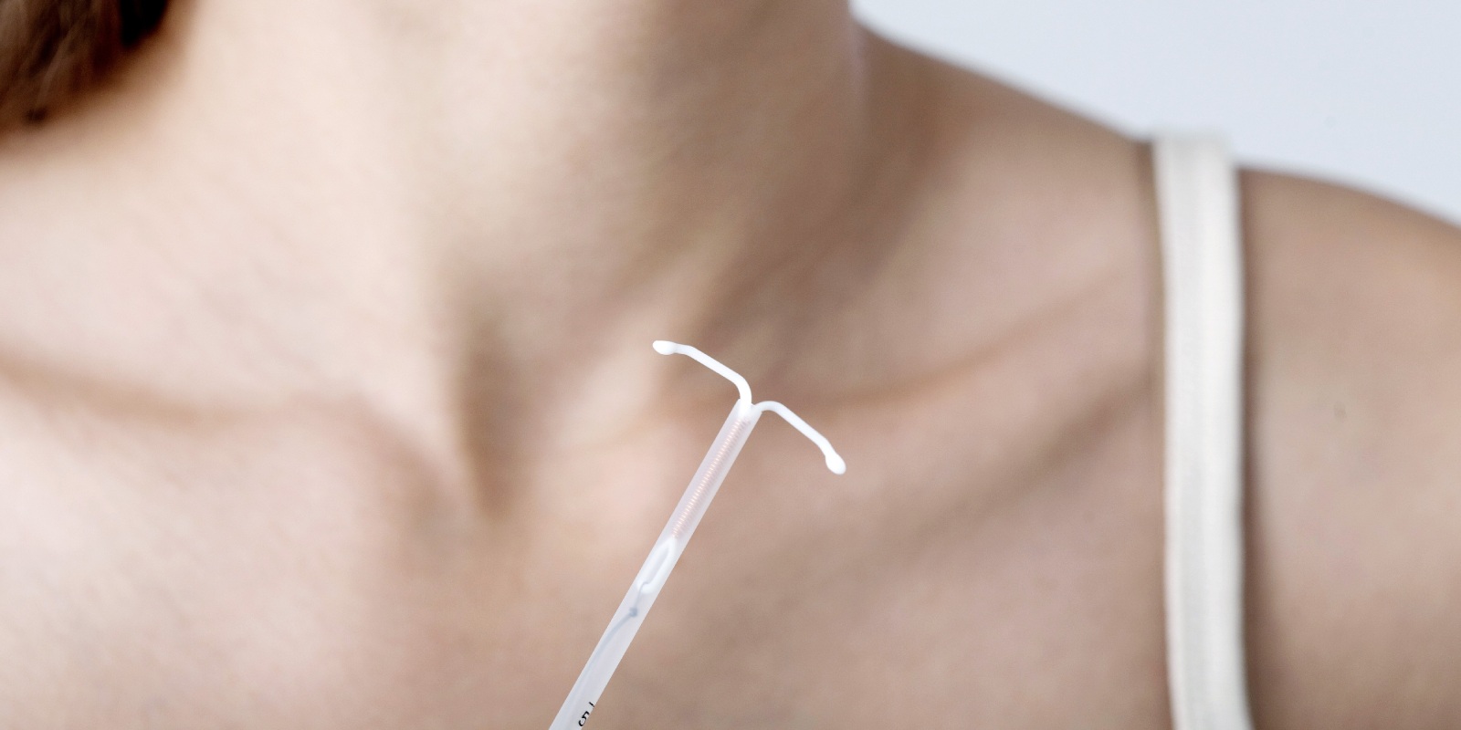 A woman and a T-shaped IUD on the foreground.There are two types of IUDs.