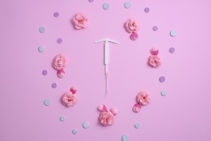 IUD placed around flowers on a pink background