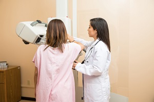 doctor and a patient standing in front of a breast tomosynthesis machine in a hospital