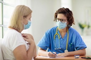 doctor examining sick patient in face mask during a GYN Wellness Screening