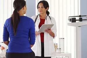 doctor talking to African American patient using pad about GYN Wellness Screening