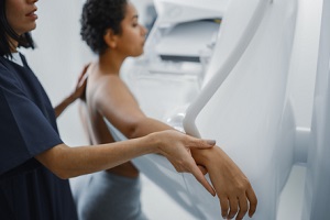female doctor explains the mammogram procedure for Breast Care to a topless latin female