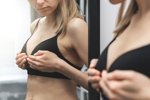 woman checking her breasts shape in front of the mirror at home for breast care