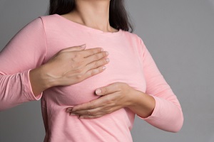 woman hand checking lumps on her breast for signs of breast cancer for breast care