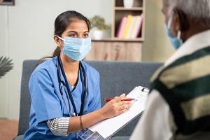 Nurse Practitioner writing prescription during home visiting to sick senior man