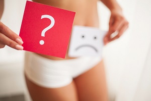 female with Menstrual Disorders holding cards with sad smiley face and question mark near her stomach