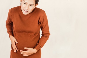 pregnant women standing with stomach pain from Menstrual Disorders