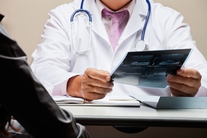 midsection of male radiologist at desk holding patient x-ray