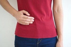 Woman showing signs of pelvic floor muscle pain by putting her hand on her waist