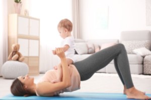 A woman is doing pelvic floor exercises with her baby inside her house