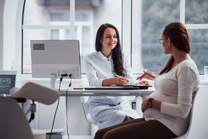 A female OB-GYN and a pregnant woman in a clinic