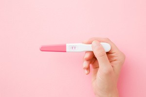A woman's hand holding a pregnancy testing kit
