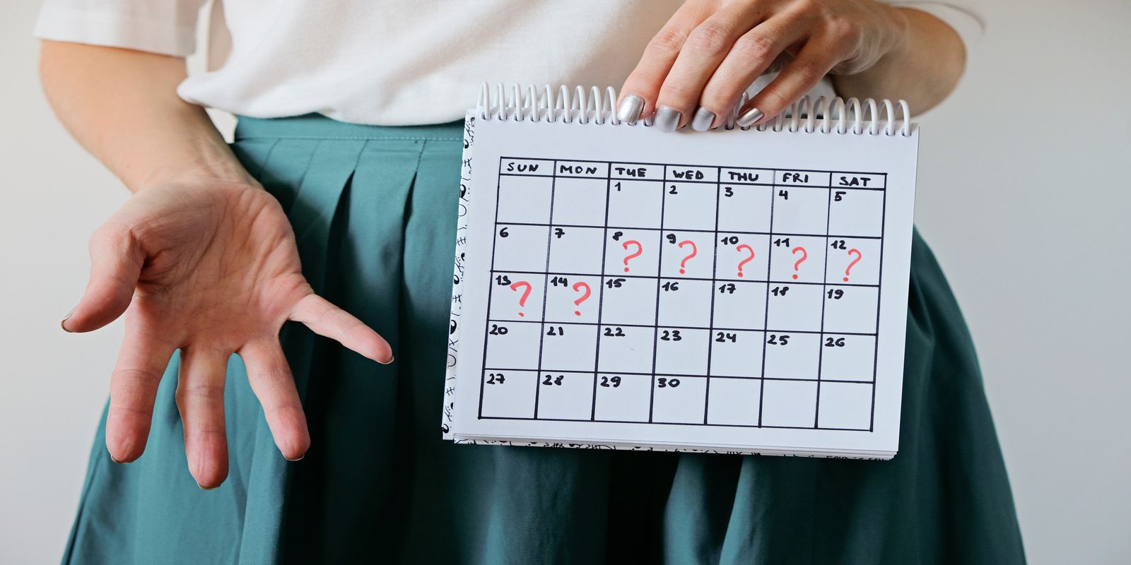 A woman in school uniform holding a calendar that shows missed periods