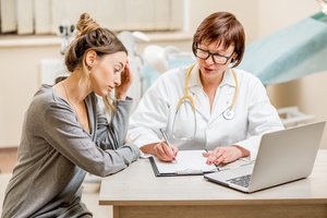 A woman looks worried while a gynecologist prescribing medicines after the checkup