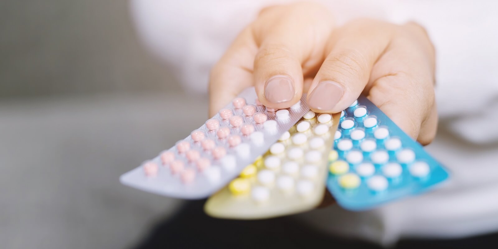 close up hand contraceptive pill on with colorful pills strips