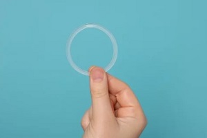 Raleigh women holding vaginal ring on cyan background