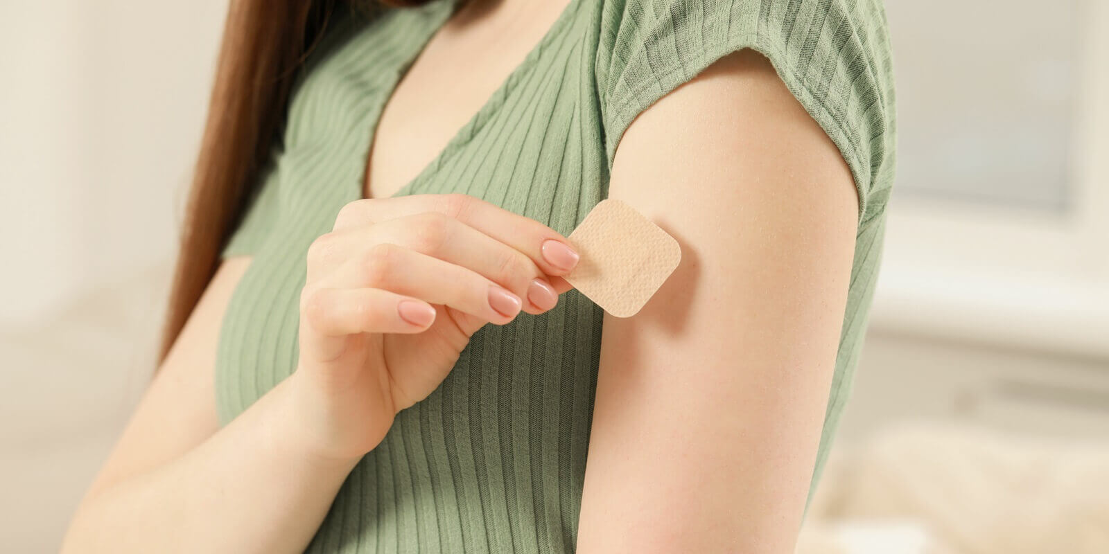 NC woman applying contraceptive patch onto her arm indoors