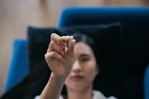 depressed asian woman lying on sofa at home holding pill