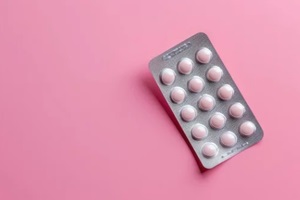 female oral contraceptive pills blister on pink background