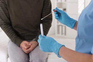 doctor taking sample for STD testing from man in clinic