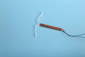 t-shaped intrauterine birth control device on light blue background