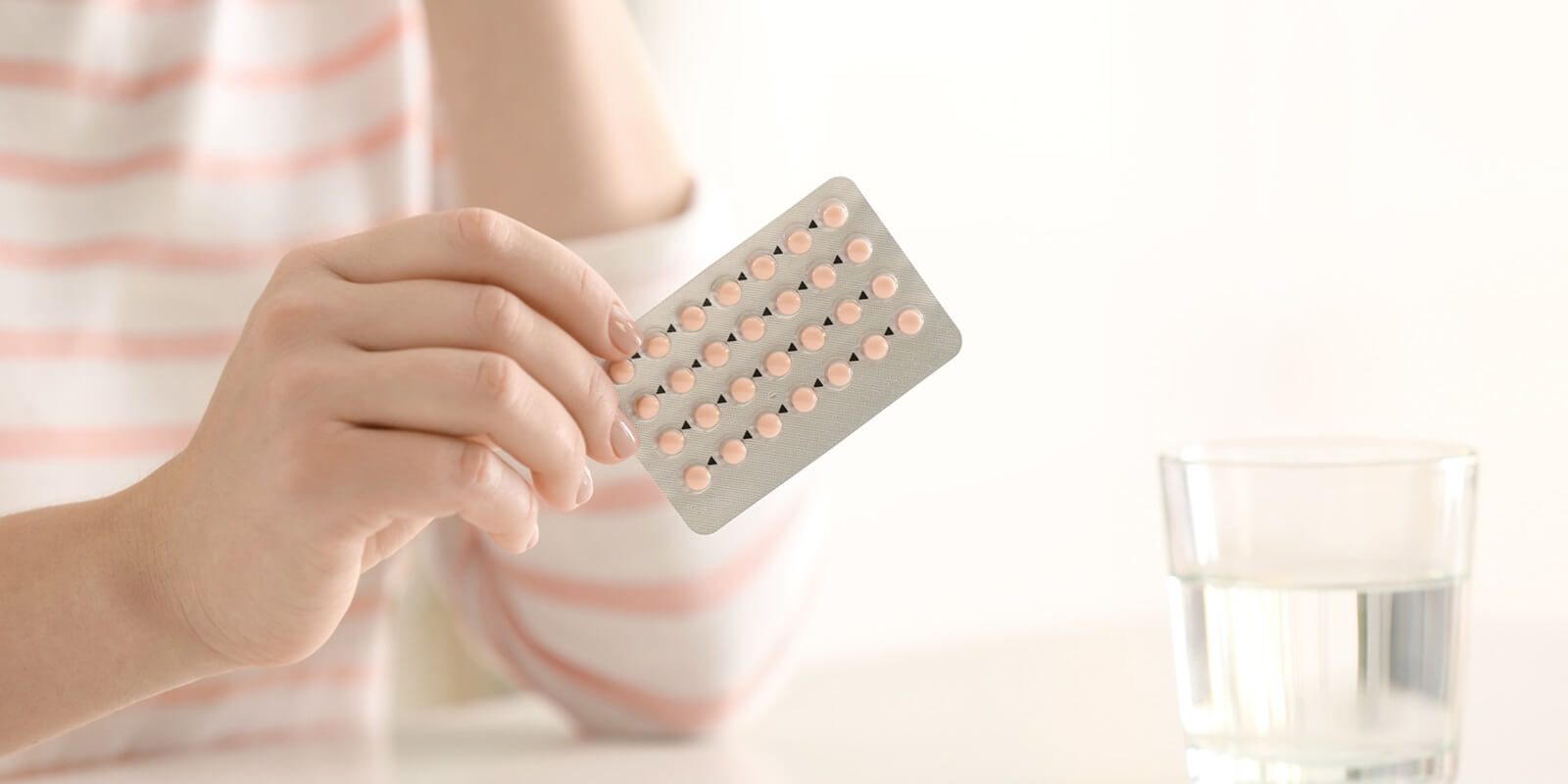 woman holding contraceptive pills at table