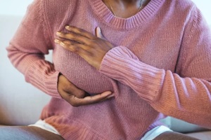 NC woman feeling menstrual cyclic breast pain, touching her chest