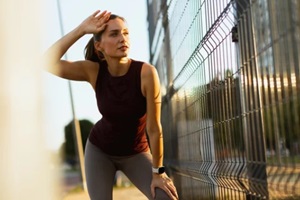 outdoor workout in Raleigh, NC at sunset with woman catching her breath along a scenic jogging path