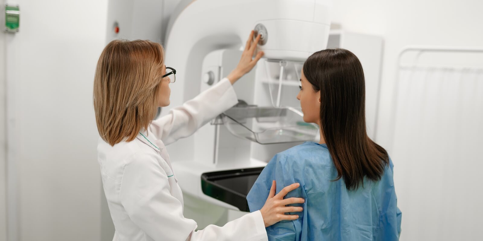 Raleigh obgyn assists a patient in a blue gown during a mammogram screening