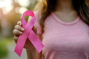 woman hand holding a pink ribbon for breast cancer awareness on blur background