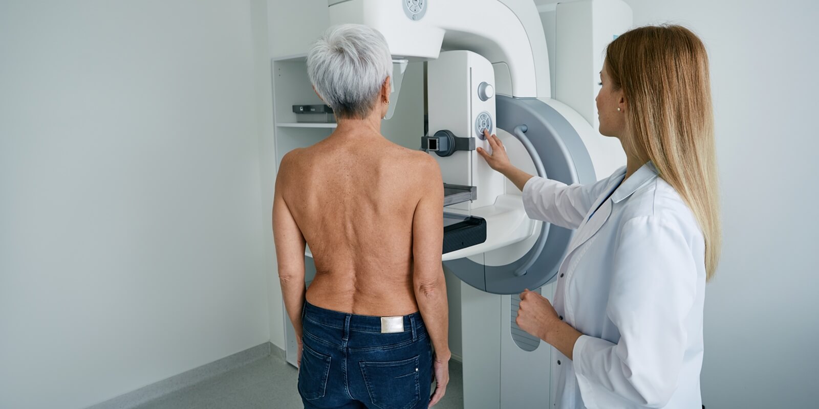 X-ray breast examination of NC female patient with radiology technician in mammography radiology room at medical clinic