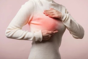 woman hands checking lumps on her breast health for signs of breast cancer on pink background