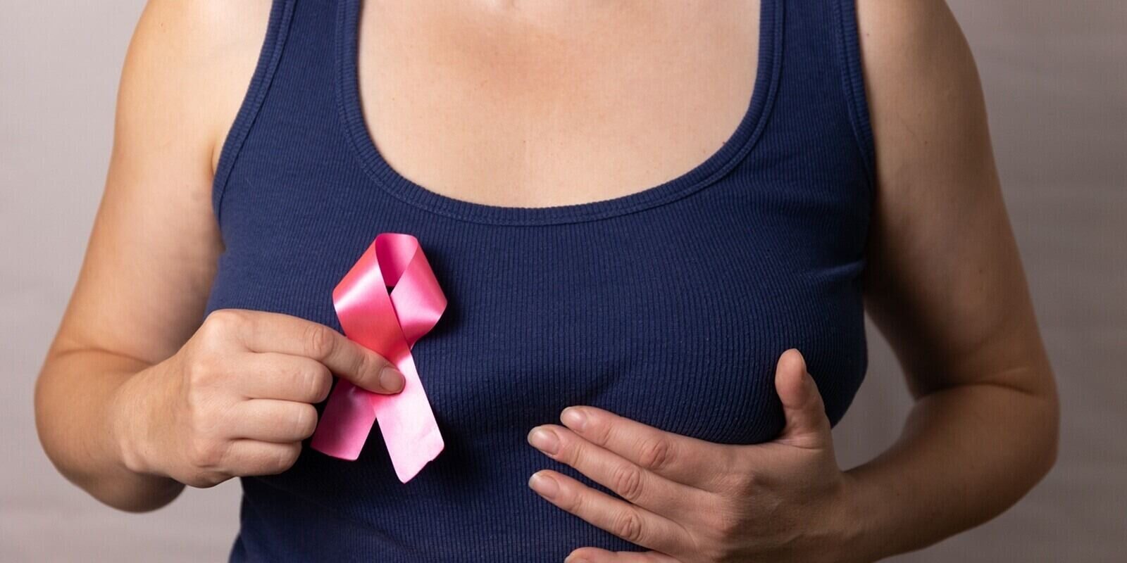 woman shows a pink ribbon, symbolizing her commitment to breast cancer awareness and support initiatives