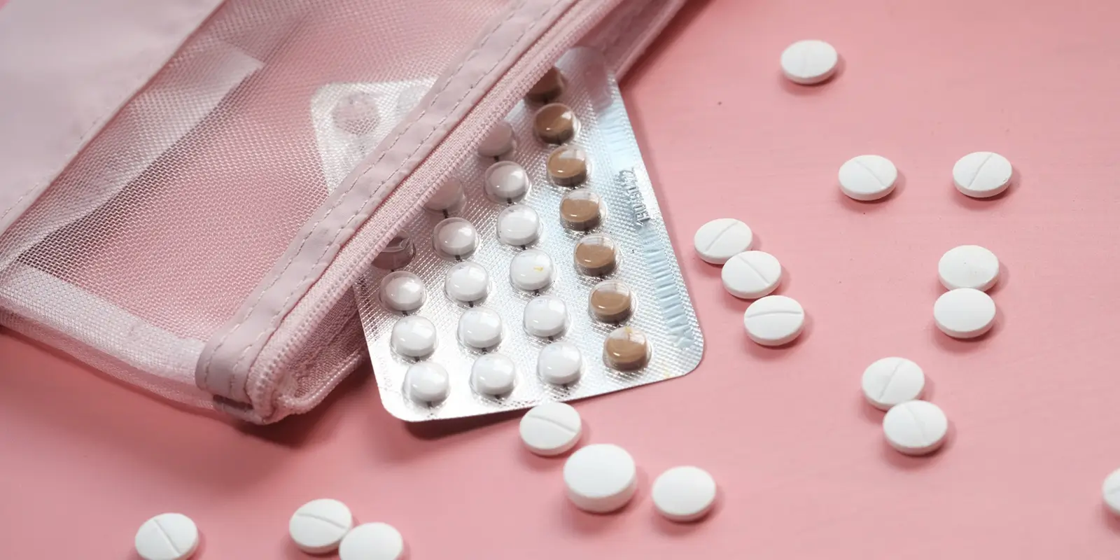birth control pills on pink background, close up