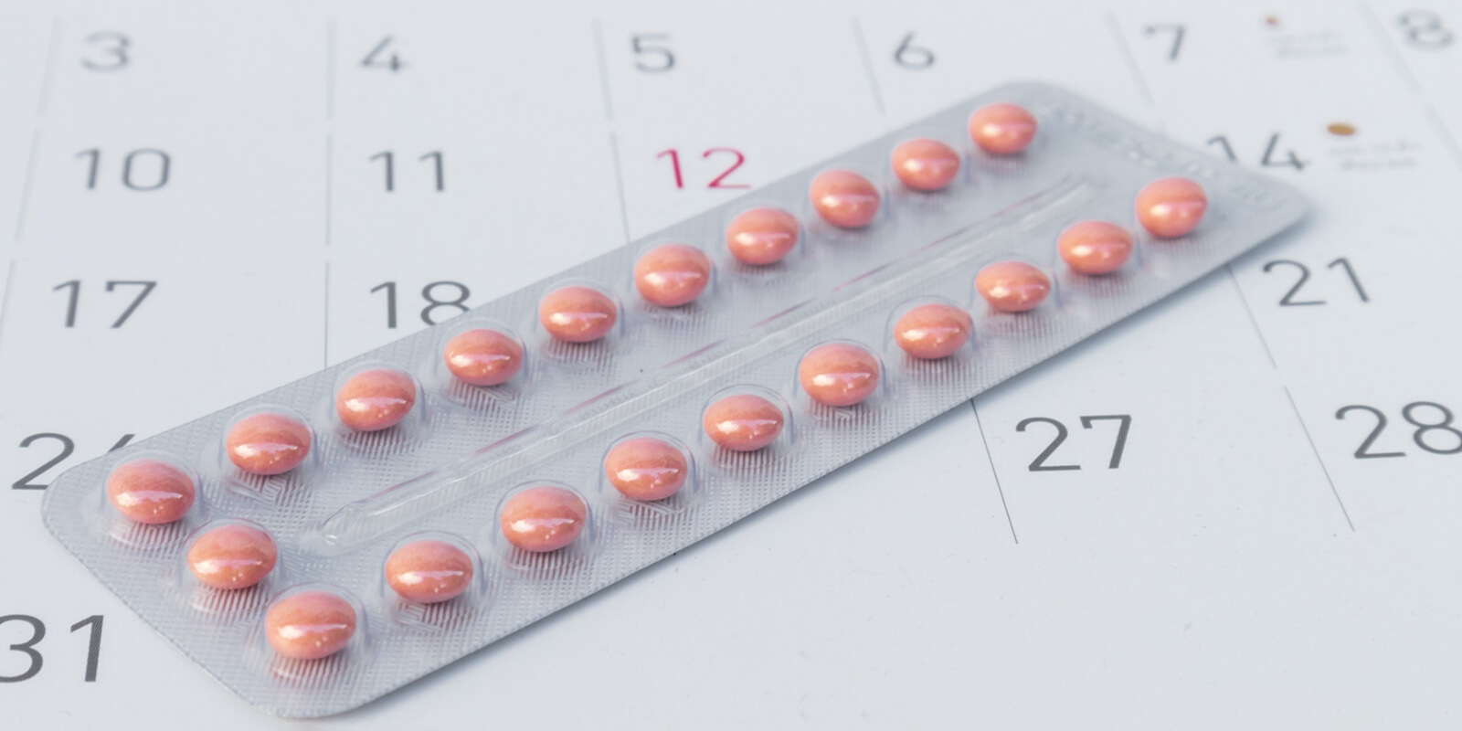 close up birth-control pill with date of calendar background for best contraceptive care practices