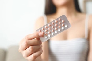 woman hands opening birth control pills in hand