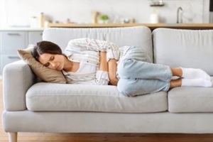 sick young female suffering from acute abdominal pain at home