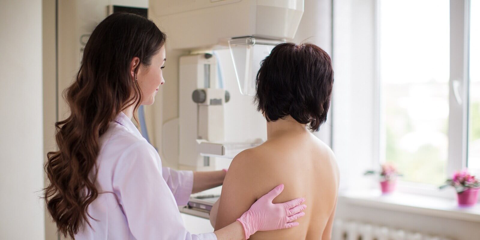 young breast specialist carrying out the mammography on Raleigh, NC patient in her exam room