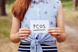 polycystic ovary syndrome, woman hormone sickness lettering on paper in womans hands