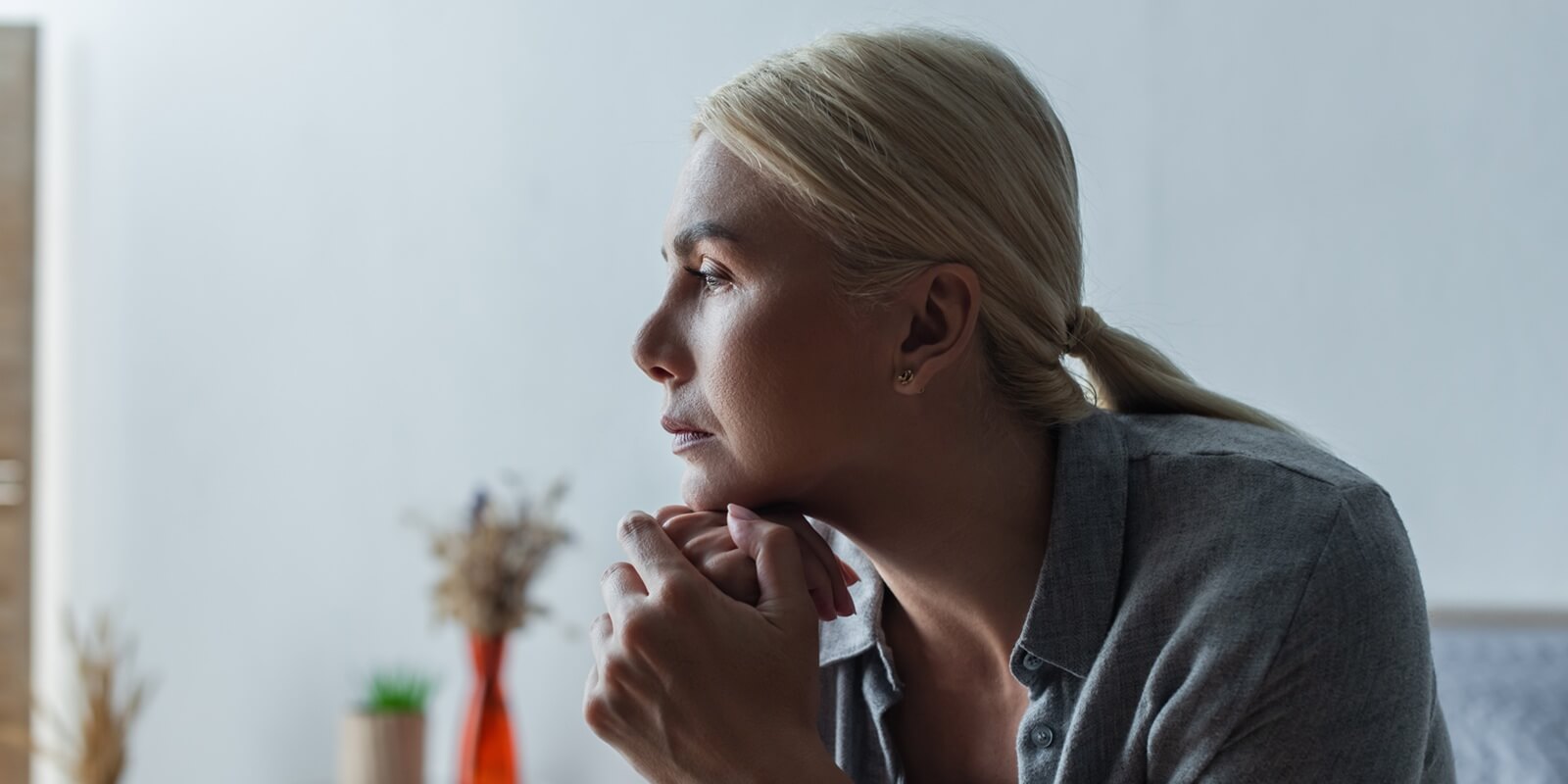 side view of worried blonde woman with menopause looking away in bedroom