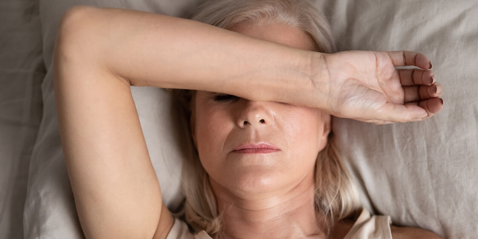 closeup melancholic woman from Raleigh, NC lying put hand on face feels unwell