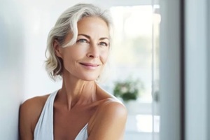 headshot of gorgeous mid age adult 50 years old blonde woman standing in bathroom after shower touching face