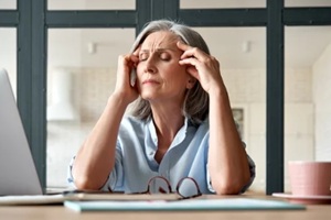 tired stressed old mature business woman suffering from headache at work