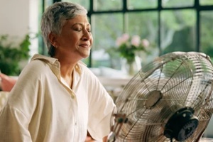 woman, hot and fan at house for heatwave, air conditioning and menopause symptoms