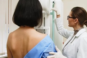 female doctor in a modern clinic explains the mammography procedure to a topless adult patient undergoing a mammogram