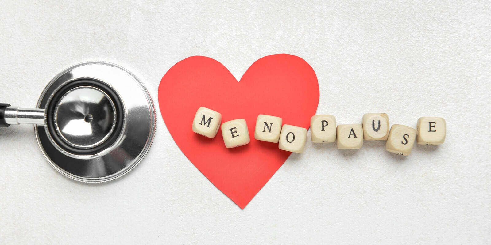 word MENOPAUSE with paper heart and stethoscope on white background - doctors who specialize in menopause
